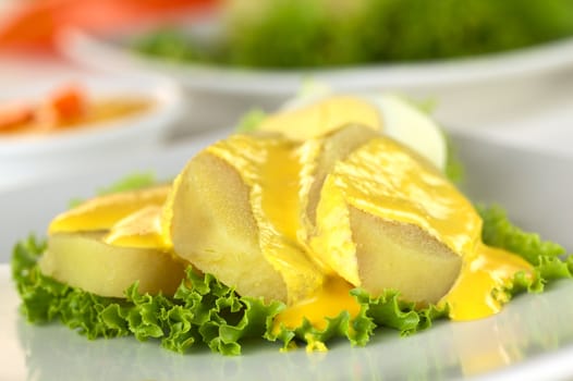 Peruvian appetizer called Papa a la Huancaina made of cooked potatoes, Huancaina sauce and boiled eggs (Selective Focus, Focus on the front of the two potato slices on the right)