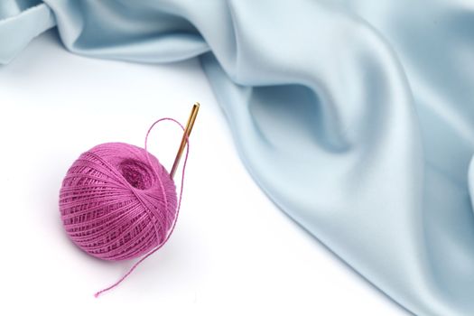 thread on blue silk background close up