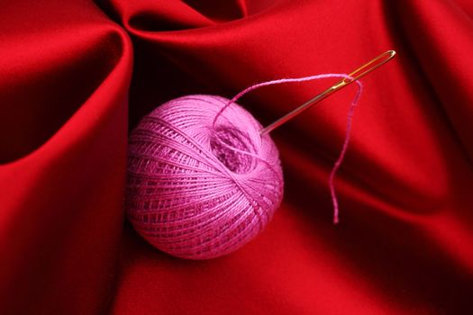 thread on red silk background close up
