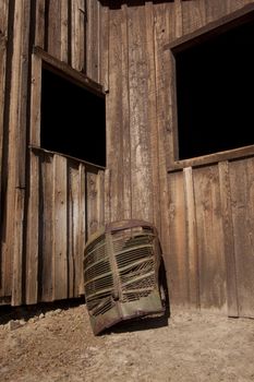 A rusty old truck grill against a barn.