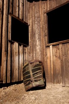 A rusty old truck grill against a barn.