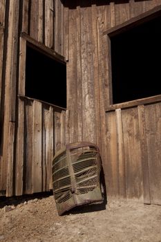 A rusty old truck grill against a barn.