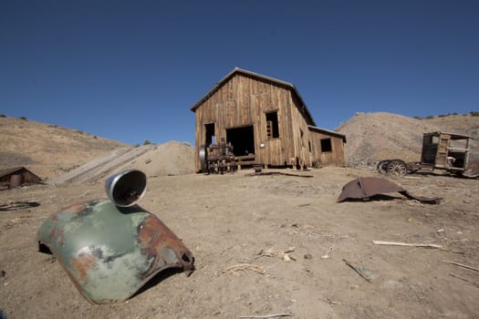 A rusty old truck fender in the forground and barn in the background.