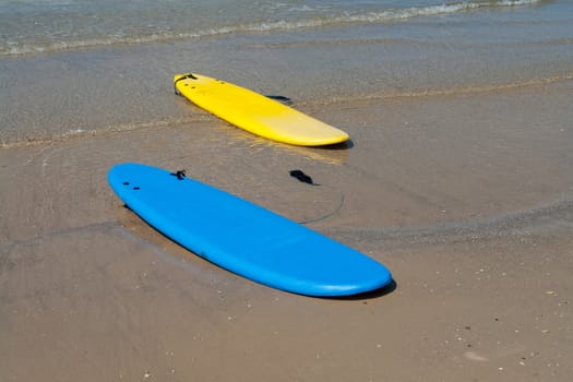 Colorfull surf boards on a  sandy beach ready for extreme action sport