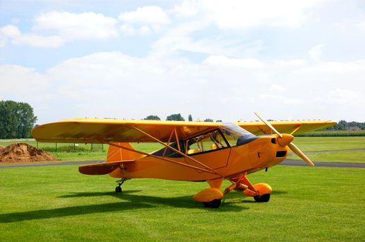 Small vintage yellow airplane on a grasfield