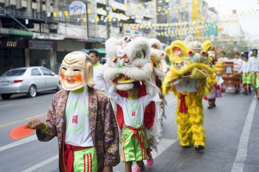 Bangkok, Thailand  -  March 27, 2011: Young boys are clothed in brightly coloured costumes  walking  in a lively procession throw Bangkok street on their way to Thai Buddhist temple.