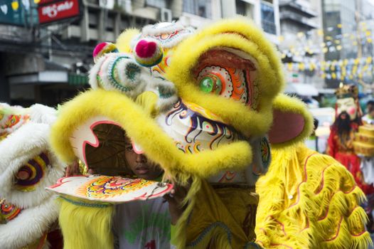 Bangkok, Thailand  -  March 27, 2011: Young boys are clothed in brightly coloured costumes  walking  in a lively procession throw Bangkok street on their way to Thai Buddhist temple.