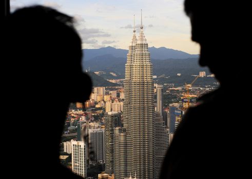 Kuala Lumpur, Malaysia - March 30, 2011: People looking to Petronas Twin Towers from viewpoint of Kuala Lumpur Tower ( Menara). The Petronas Towers are the tallest twin buildings in the world.