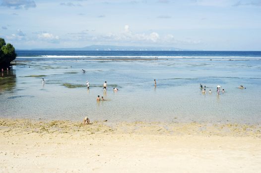Nusa dua, Bali, Indonesia - April 17, 2011: People swimming in the ocean during tide ebb. Nusa Dua is known as an enclave of large international 5-star resorts in south-eastern Bali.