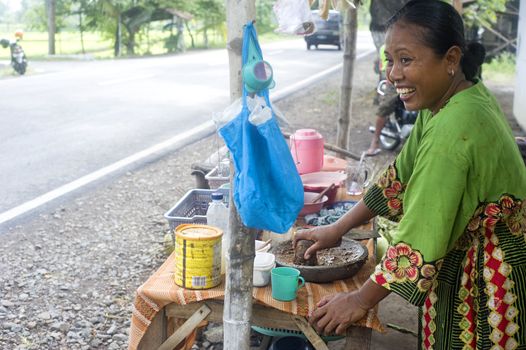 Java,Indonesia - April 21,2011: A smiling woman preparing fast food near the road
