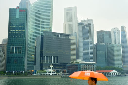 Singapore, Republic of Singapore - May 05, 2011: Man with ubrella in the rain in Singapore. Singapore has long been recognised as one of the best cities for business.