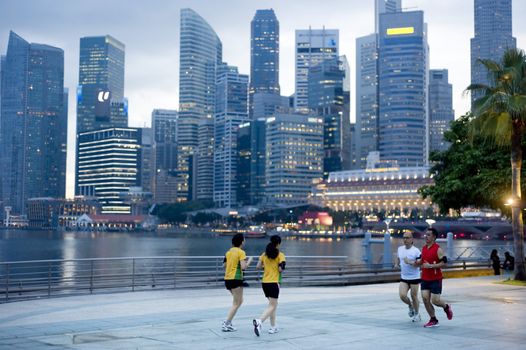 Singapore, Republic of Singapore - May 3, 2011: People running in the evening on embankment in front of business center. Running is very popular sports in Singapore