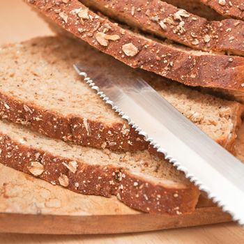 Sliced wholemeal bread and a bread knife on a wooden board