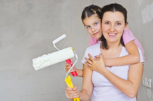 Portrait happy mother and douther with roller for painting a wall