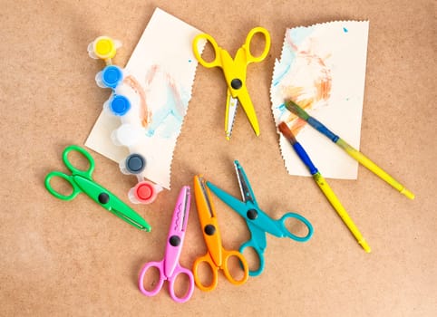 Scissors, paper, paint and brushes on a wooden surface