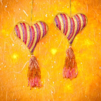 Two heart decorations hanging against a grungy background