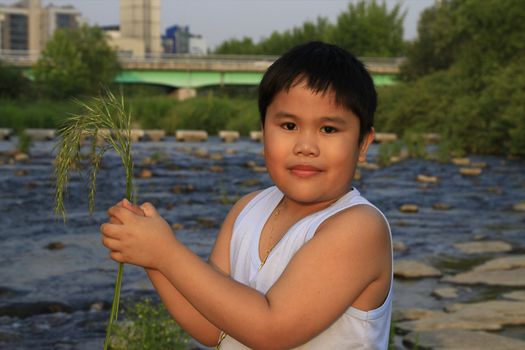 asian boy holding grass in a river set-up.