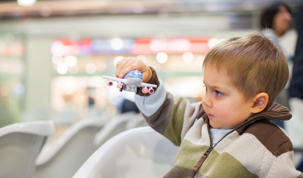 Cute little boy playing with a toy airplane in airport