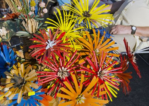 Outdoor market fair sell decorative colorful handmade artificial flowers made of natural materials cone and so on.