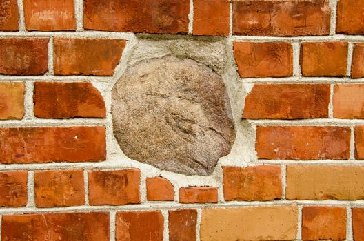 Big stone in red brick wall. Architecture closeup background details.