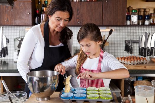 Mother and daughter filling cupcakes in the kitchen