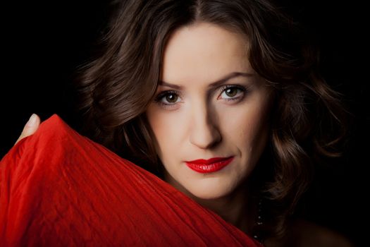 Closeup portrait of young beautiful girl with makeup in red on a black background