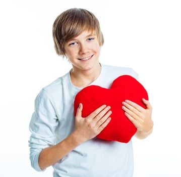 A cute young boy in love with a red plush heart in his hands. Focus on the heart.