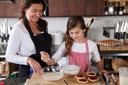 Mother and daughter measuring ingredients for tarts in the kitchen