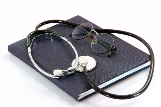 spectacles and phonendoscope on book health and medical objects isolated on white background