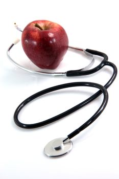 healthy food red apple and phonendoscope health and medical objects isolated on white background vertical focus on the phone and  blur on apple
