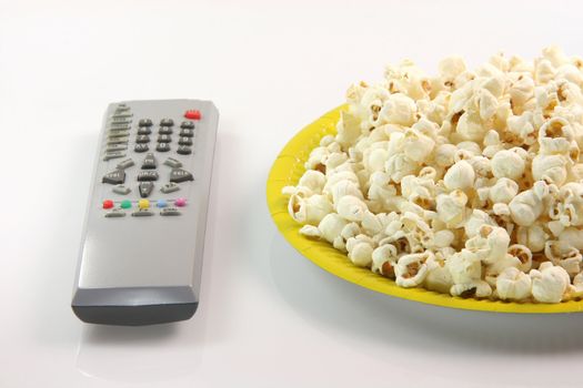 yellow paper plate with pop corn and television remote control food and entertainment conceps