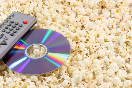 television remote control and dvd disc movie on pop corn background food and entertainment conceps