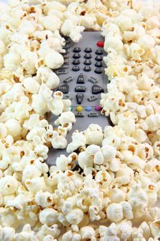 television remote control under  pop corn background food and entertainment conceps