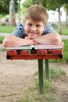 schoolboy reads the book on a bench in park