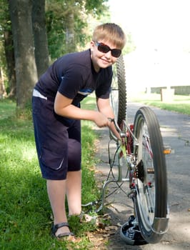 little boy repairs a bicycle in a summer park