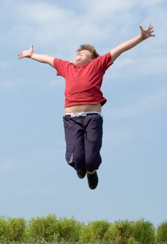 A little boy jumps with sky at background 