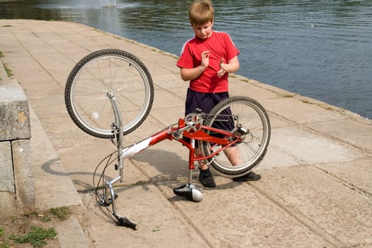 little boy repairs the bicycle on quay