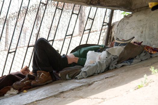 The homeless person sleeps under the bridge