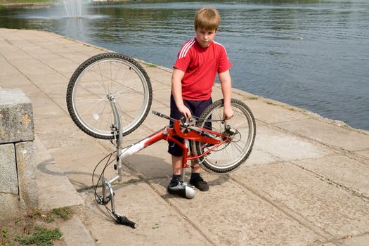 little boy repairs the bicycle on quay