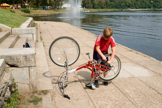 little boy repairs the bicycle on quay