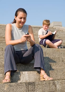 girl with mobile phone on a stone staircase. boy reads book