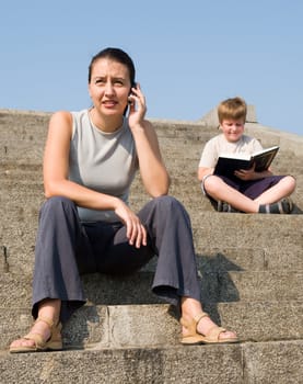 girl with mobile phone on a stone staircase. boy reads book