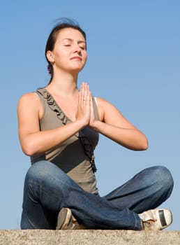 Meditation. The girl meditates with sky at background.