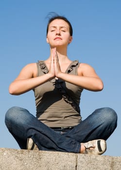 Meditation. The girl meditates with sky at background.