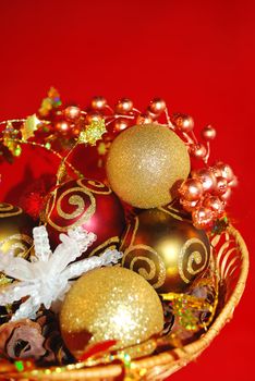 Christmas ornaments in small basket located on the red background.