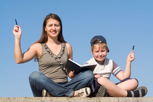 Family with book and pens on a sky background