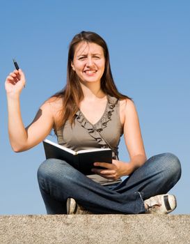 girl with writing-book and pen on a sky background