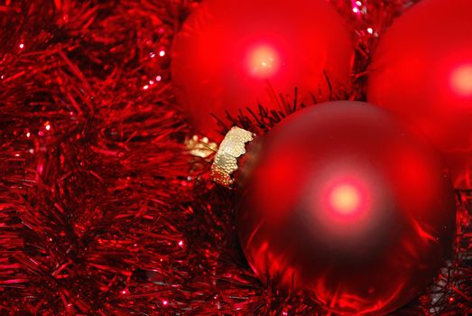 Red Christmas ornaments are on the sparcly background. 