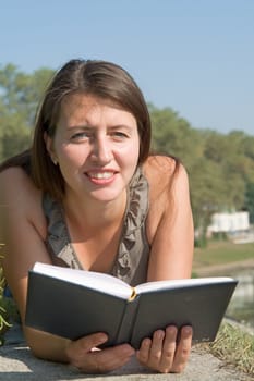 girl reads book with sky at background