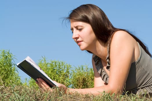 girl reads book with sky at background